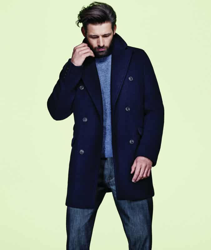 Man wearing pea coat, cashmere jumper and dark jeans