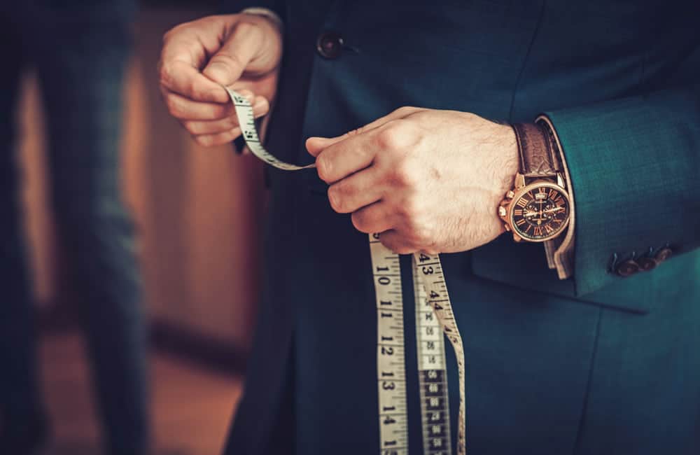 a tailor measuring a customer for a bespoke suit