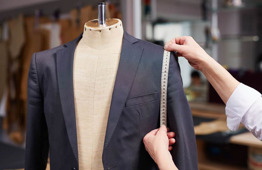 a tailor measures a bespoke suit jacket