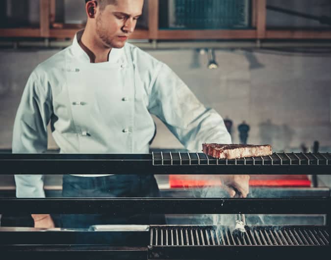 Man cooking a steak in a professional kitchen