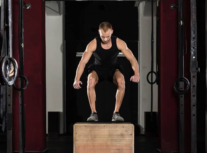 Man doing box jumps in between burpees