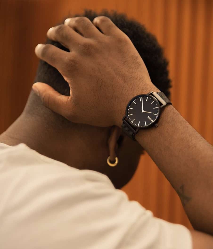 man displaying a watch with his hand on the back of his head