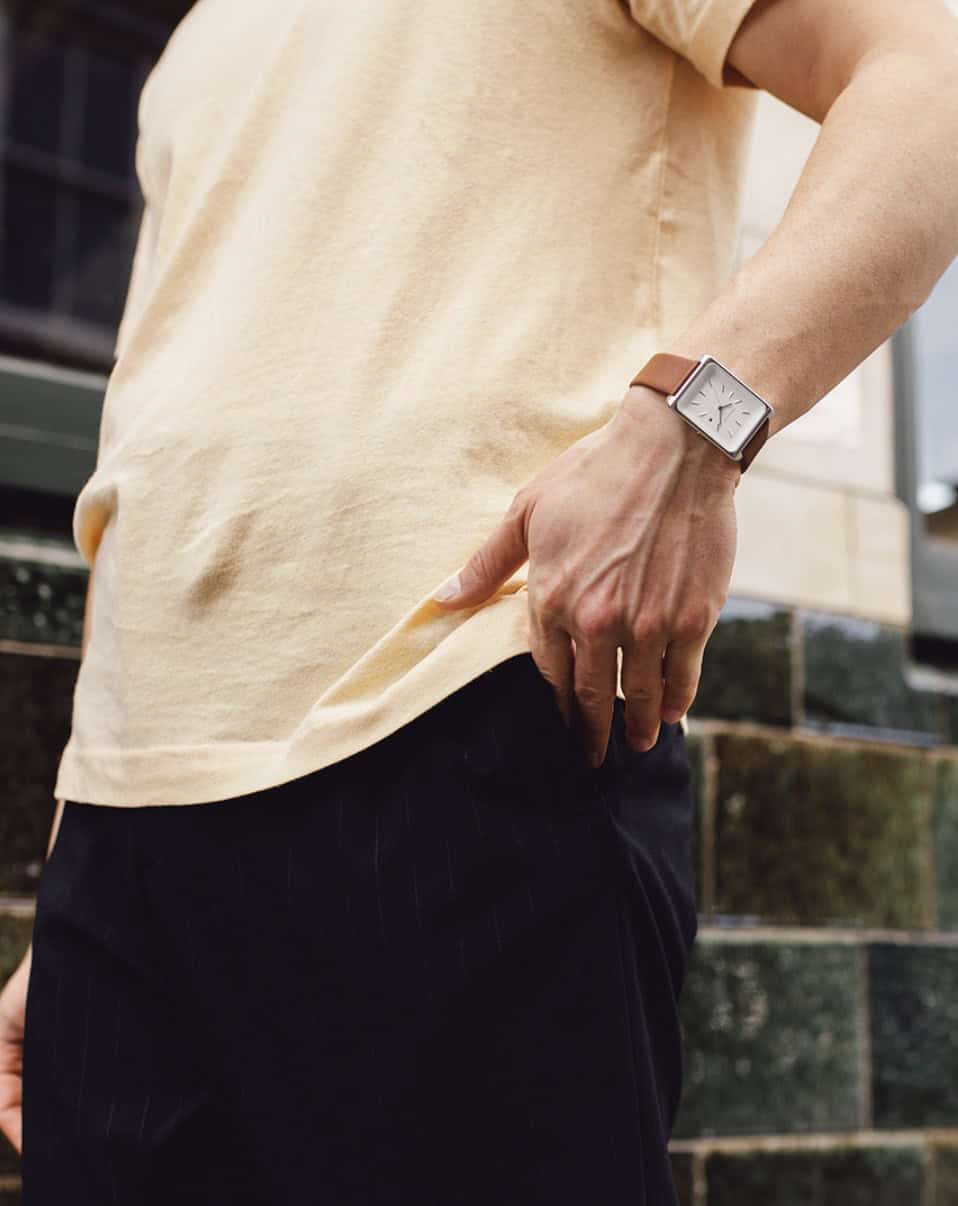 man wearing a square watch putting his hand into his wallet