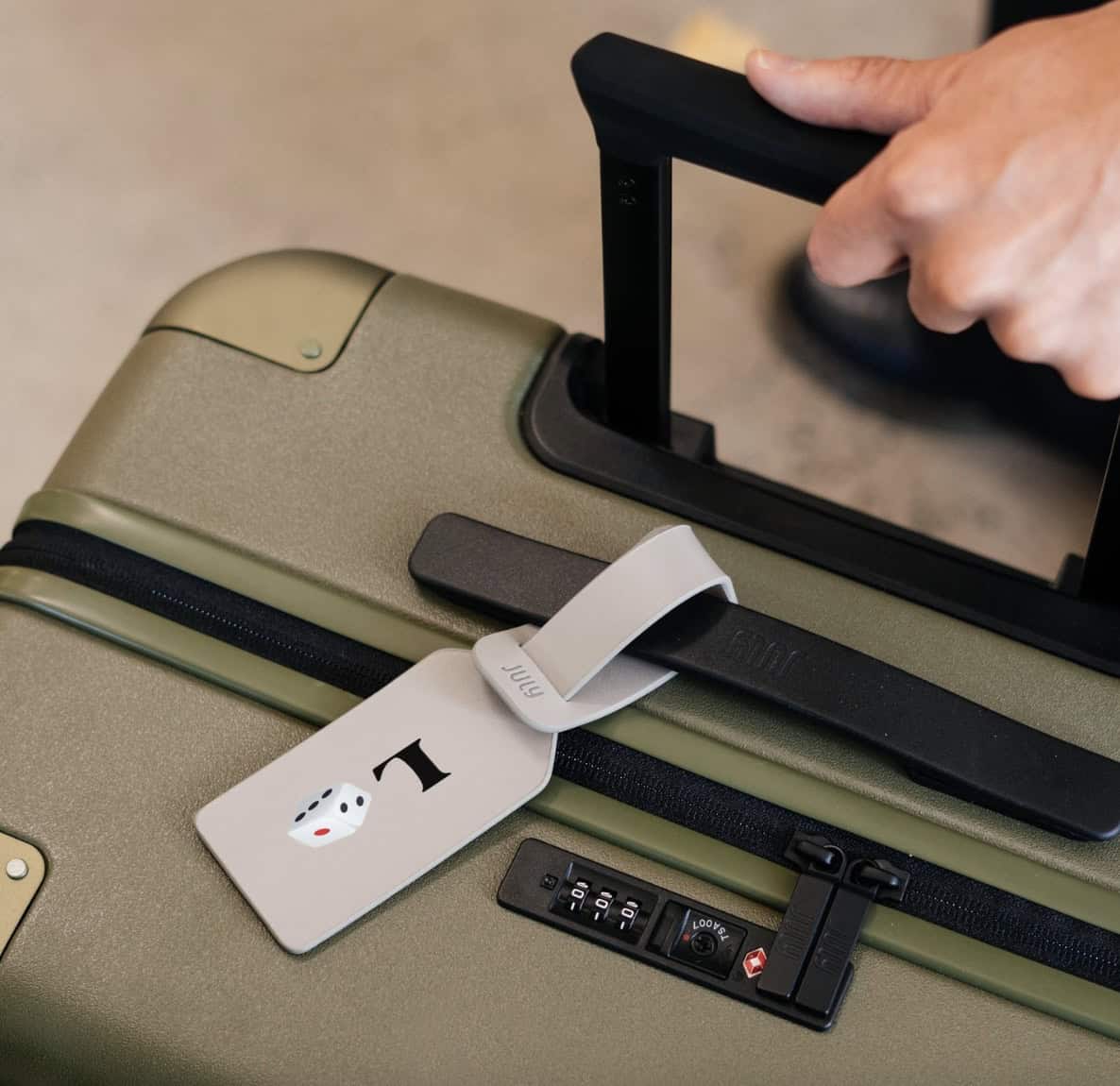 Hand on a green hardshell piece of luggage