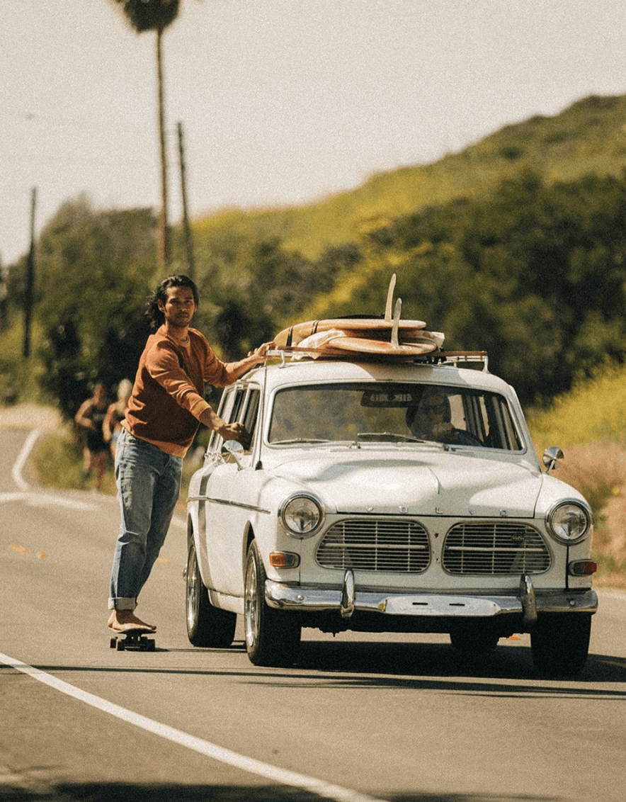 Man skateboarding holding onto a car inwork pants for men