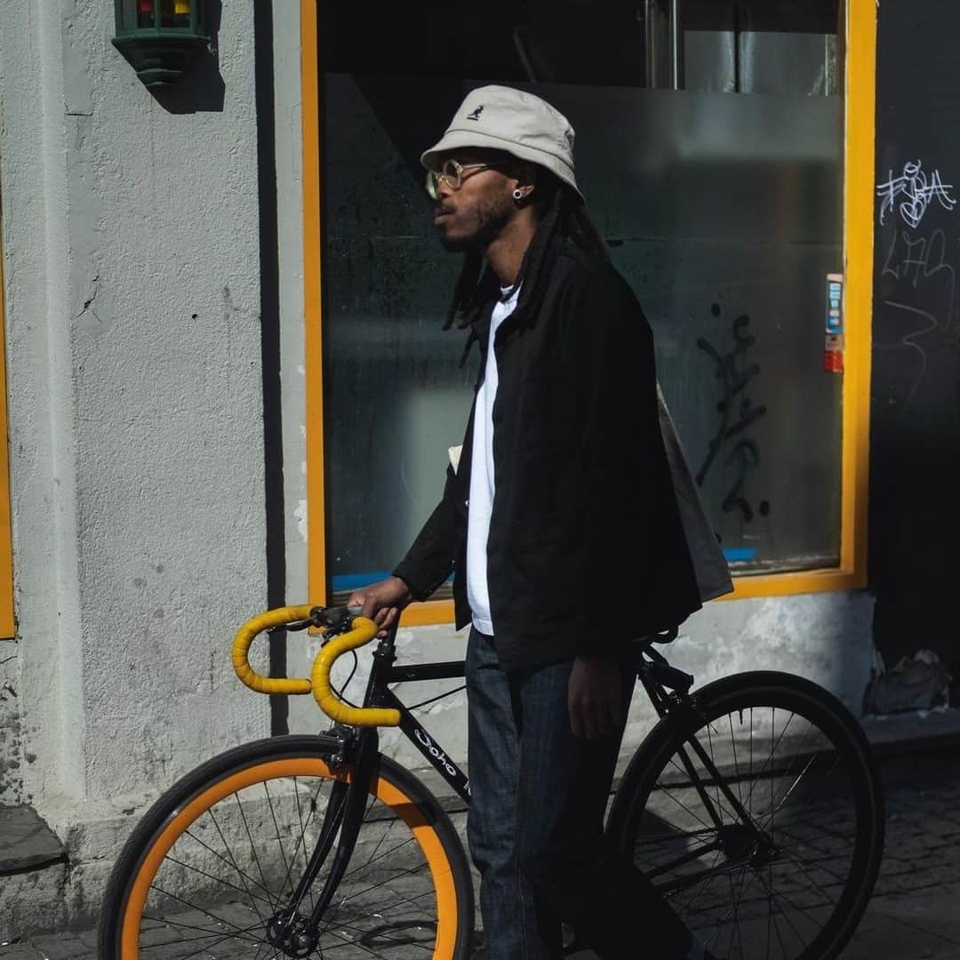 man in a bucket hat pushing a fixie road bike