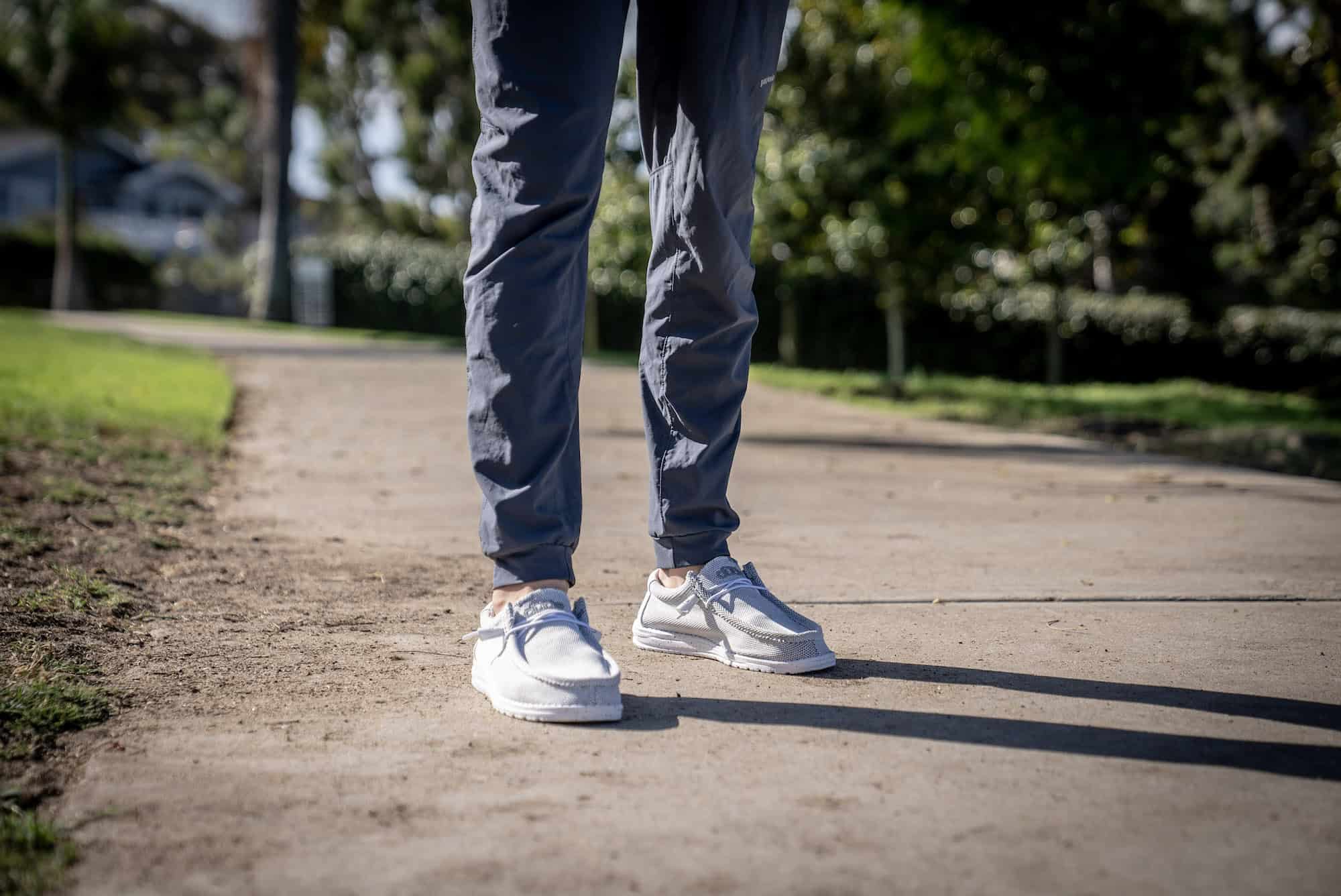 man standing on sidewalk wearing hey dude shoes and grey joggers