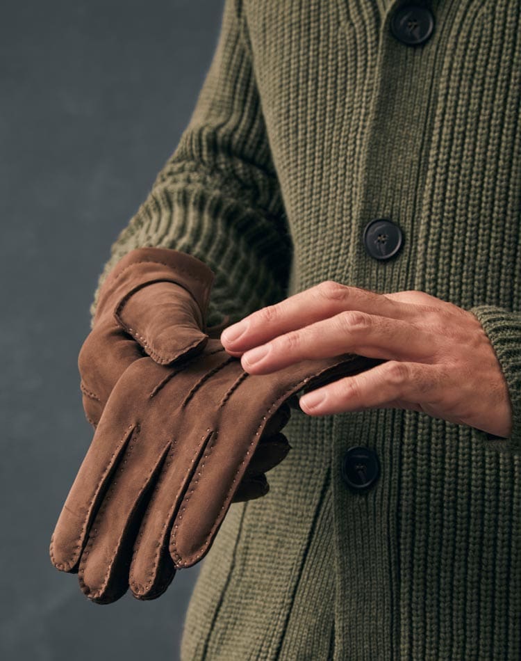 Man putting on brown leather gloves