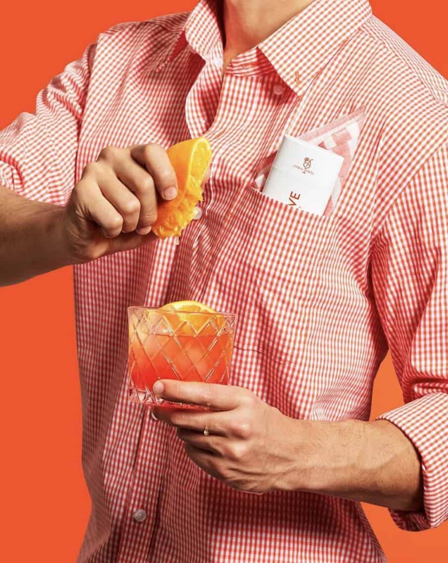 Man squeezing an orange into a drink