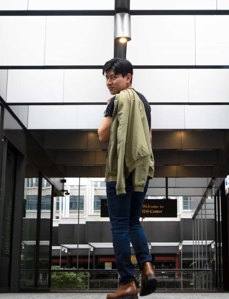 man with his jacket slung over his shoulder looking behind him