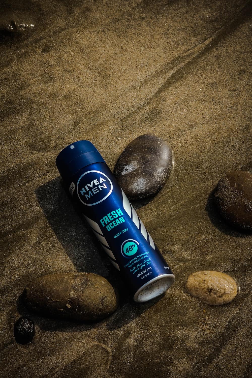 Spray deodorant bottle leaning against rocks, low lighting 