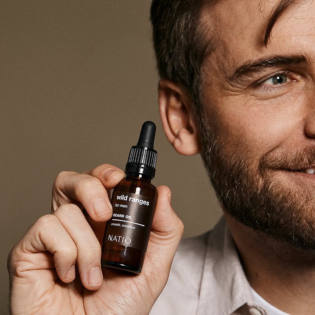 Man holding a bottle of beard growth oil