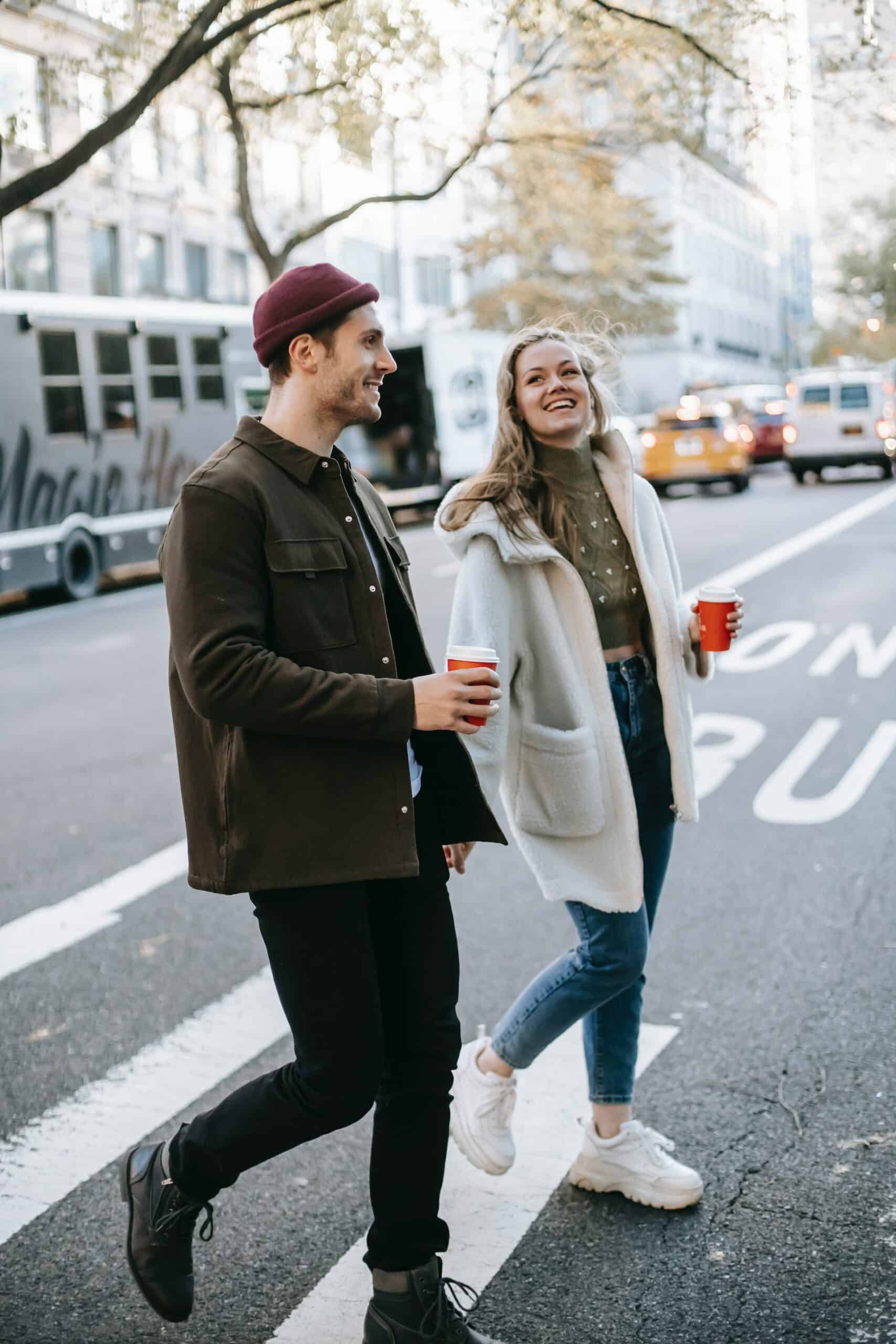 Couple crossing the street with drinks in their hands