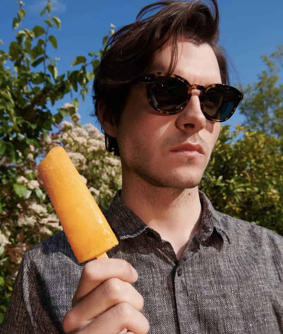man holding a popsicle and wearing polarized sunglasses