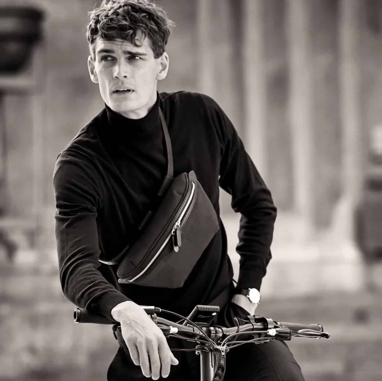 Man leaning on a bike wearing a cross-body bag for men