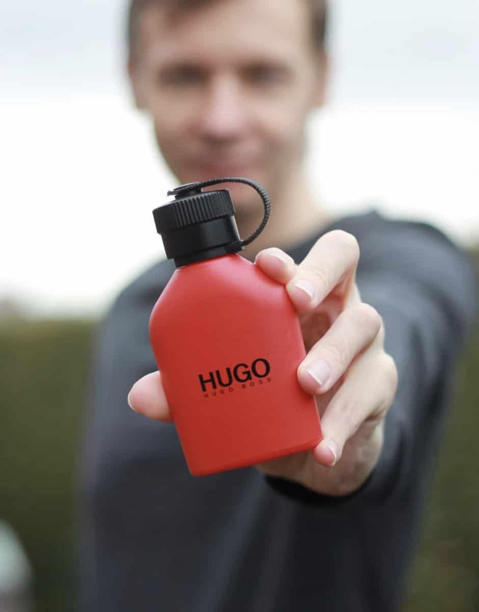 man holding up a bottle of hugo boss cologne