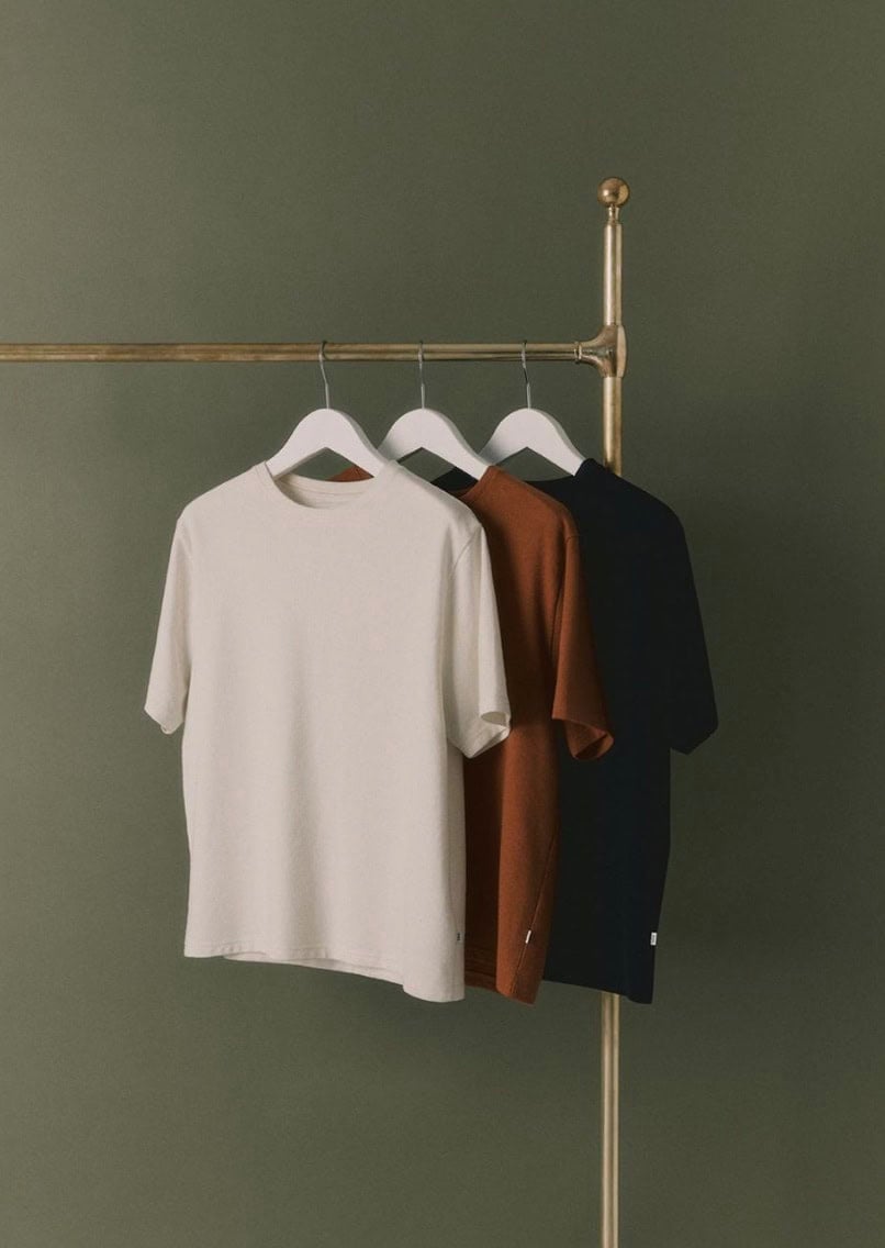 gold clothing rack with t-shirts hanging off them