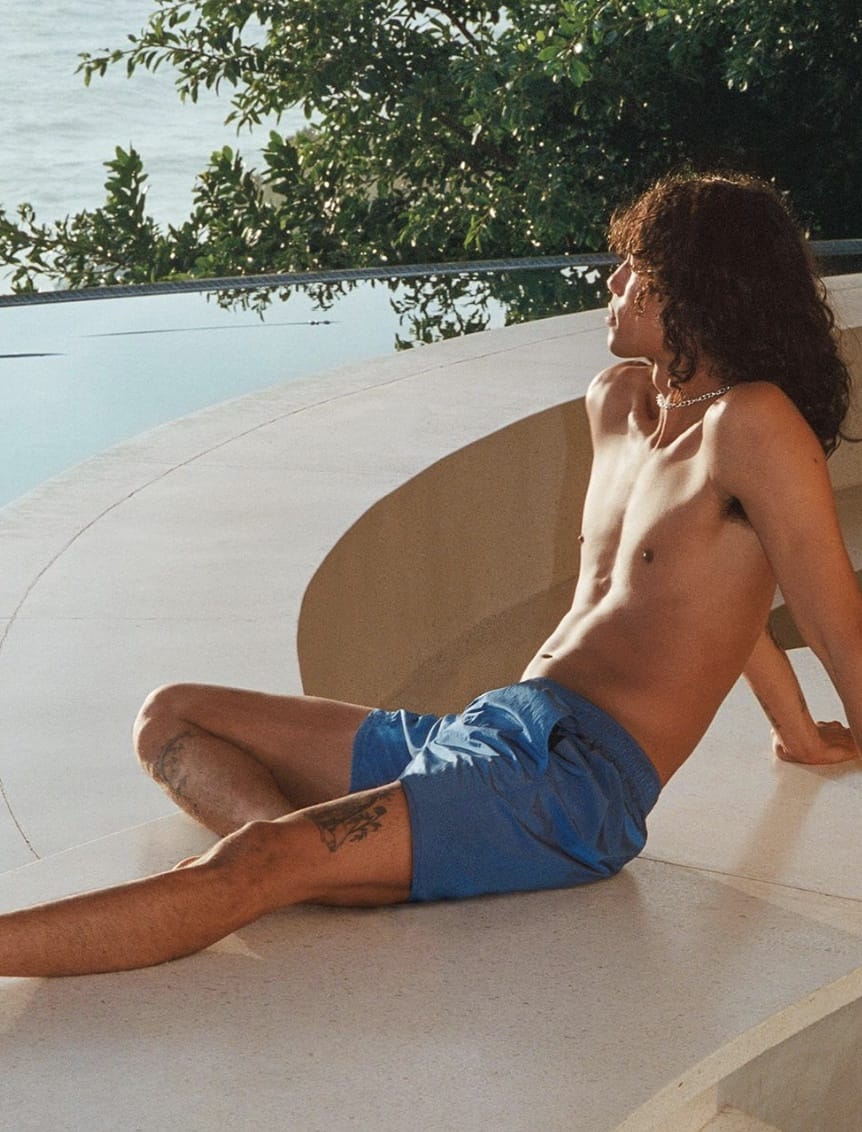 man sitting by a pool, looking away from the camera