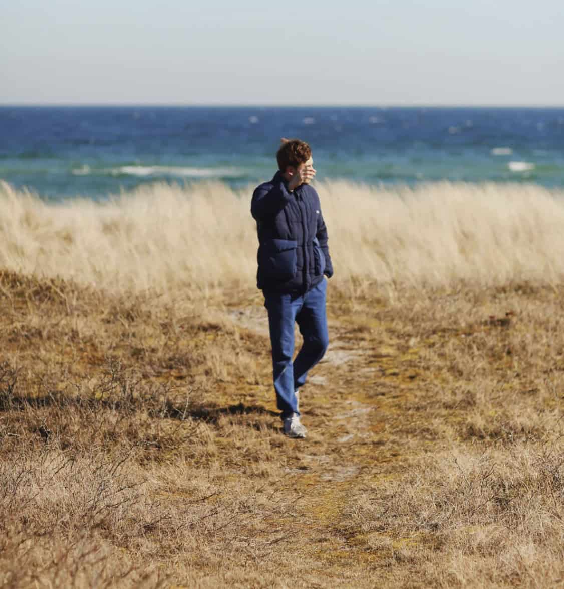 Man walking on a beach in a puffer jacket