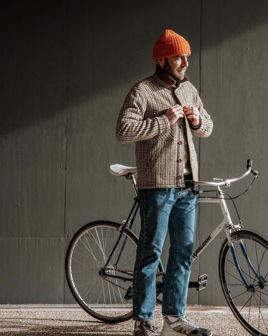 man buttoning his shirt with his bike leaning against him