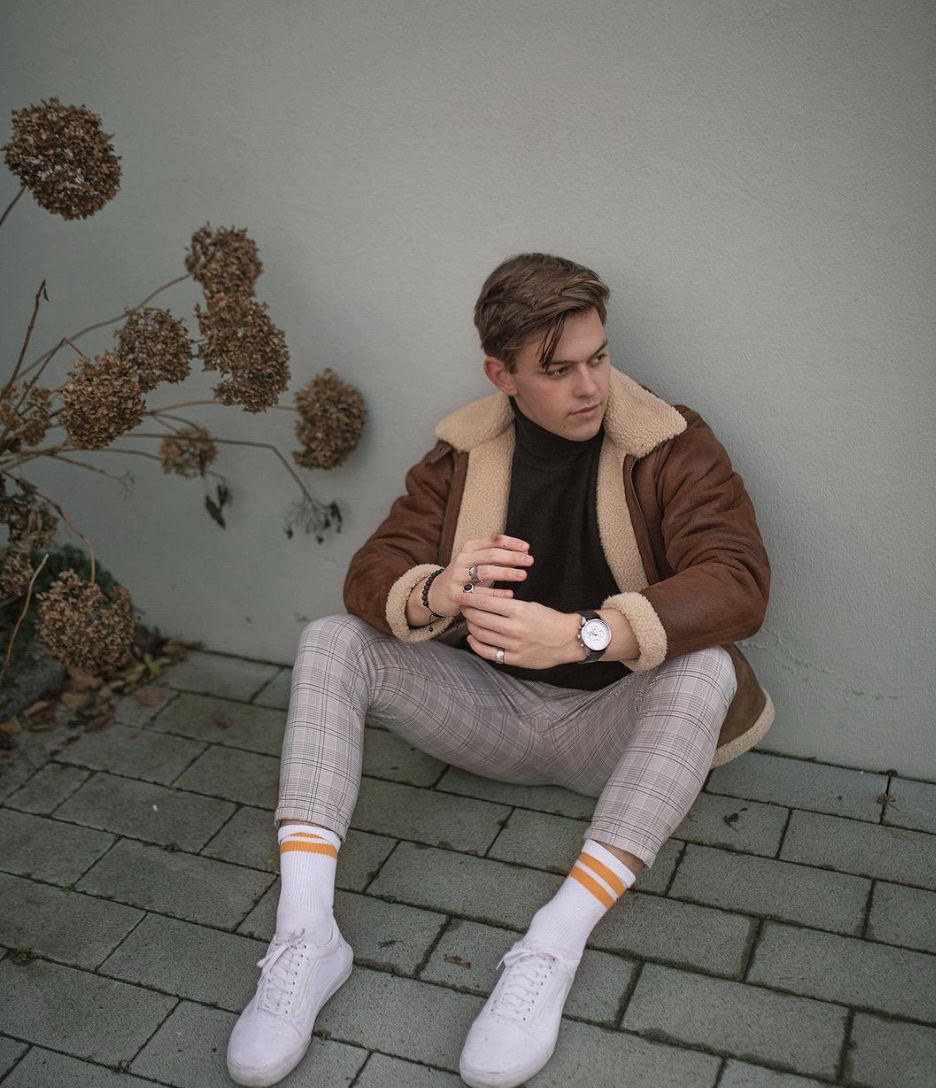 man sitting on the ground wearing white vans adjusting his watch