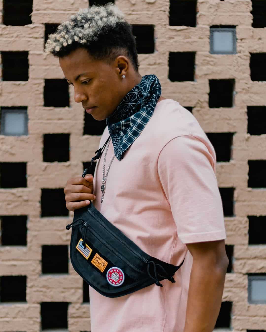 Man wearing a pick shirt, a neck bandana, and a cross-body fanny pack
