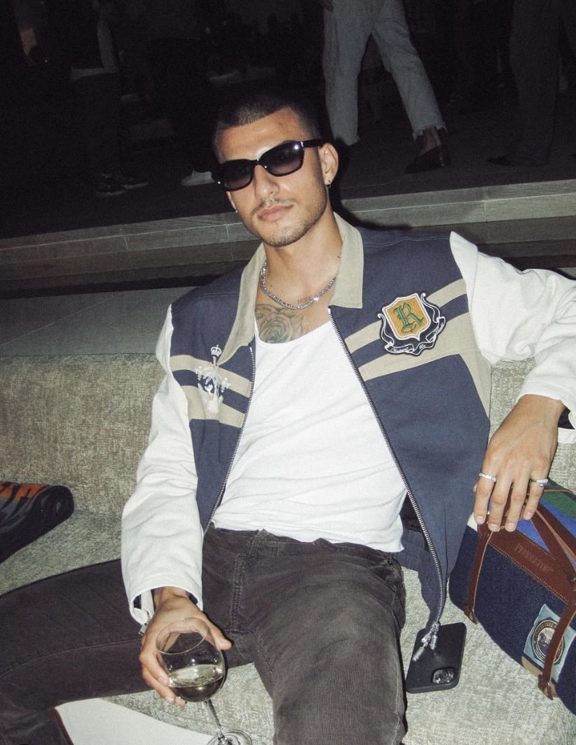 man leaning back at night with sunglasses on and a glass of wine in hand
