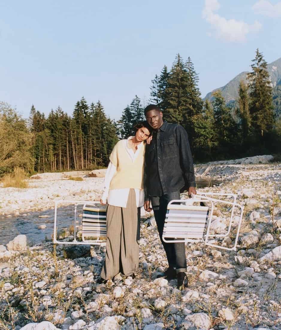 Man and women in a river rock bed holding chairs