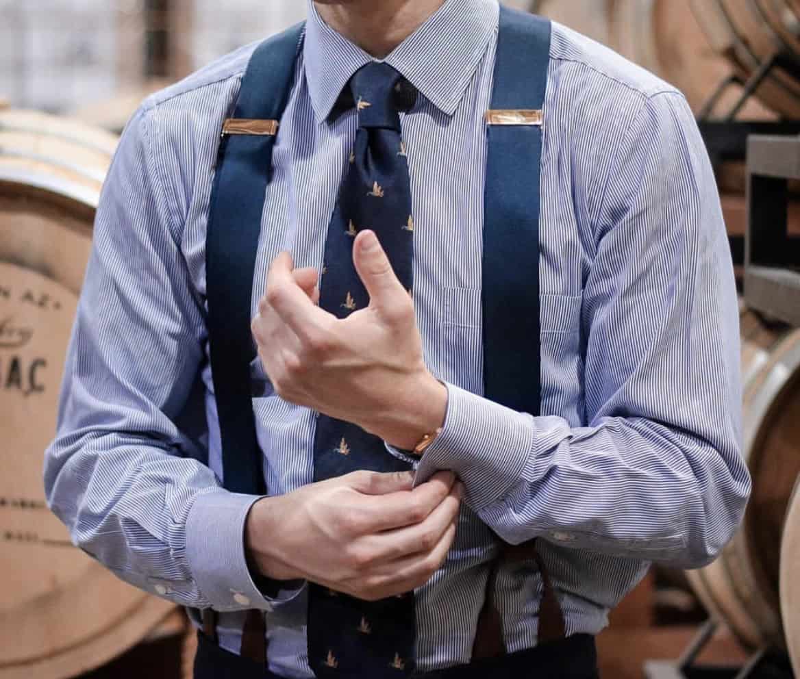 man in a dress shirt, suspenders and tie, adjusting his sleeves 