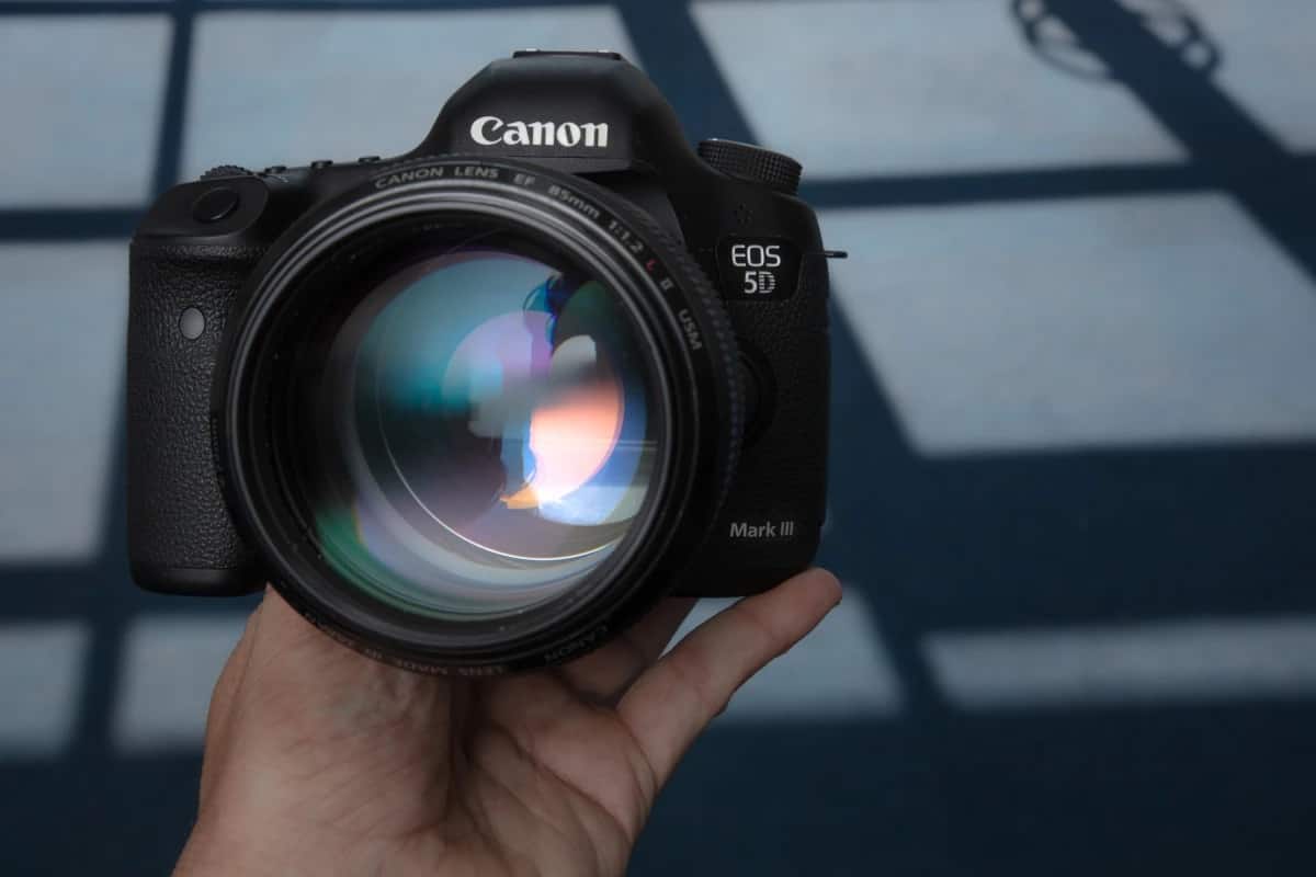 someone holding a camera with the lens posted towards the camera