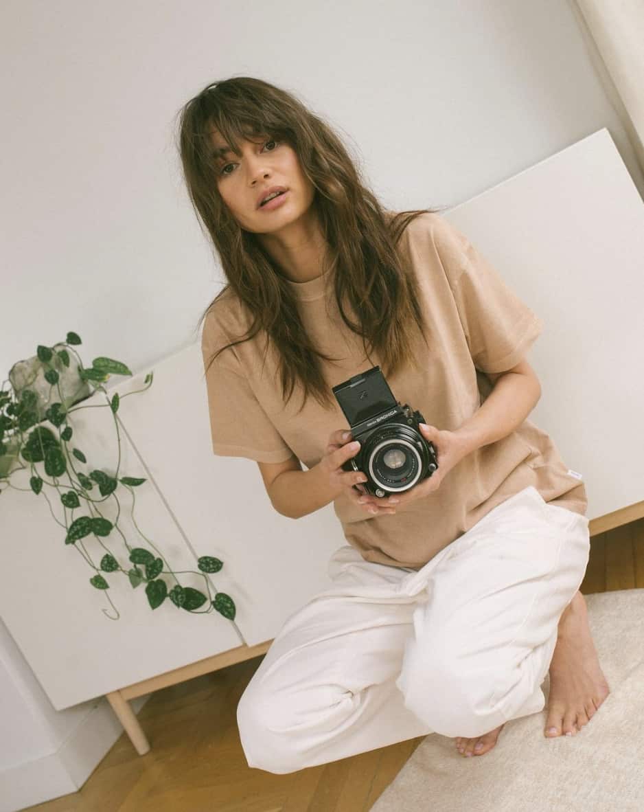 woman kneeling down with a camera, looking into the camera