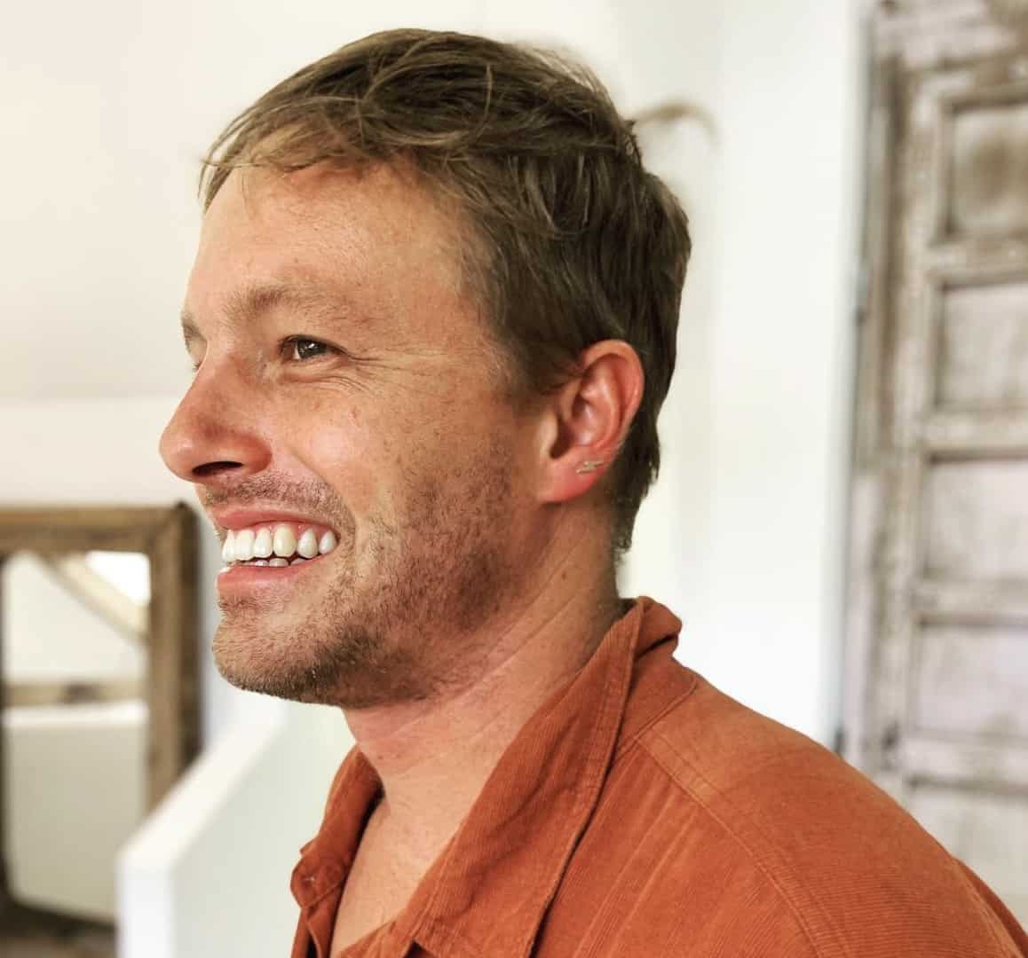 man smiling showing off an upper lobe piercing