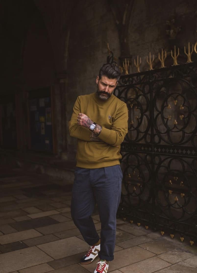 man with his arms crossed, looking down at the ground