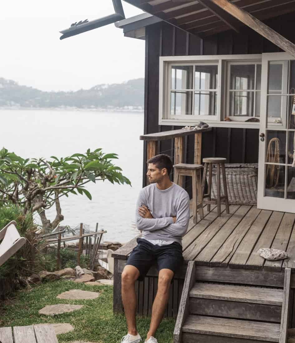 man sitting on a porch wearing shorts and a long sleeve t-shirt