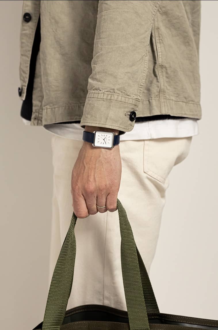 man holding a tote bag showing off a monofore square watch
