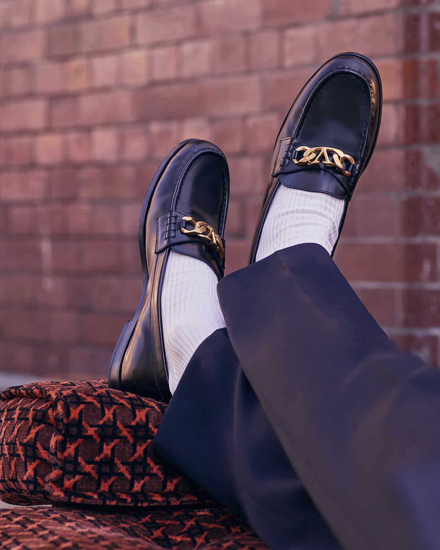 Classic Valentino calfskin loafers are detailed with a bold logo chain