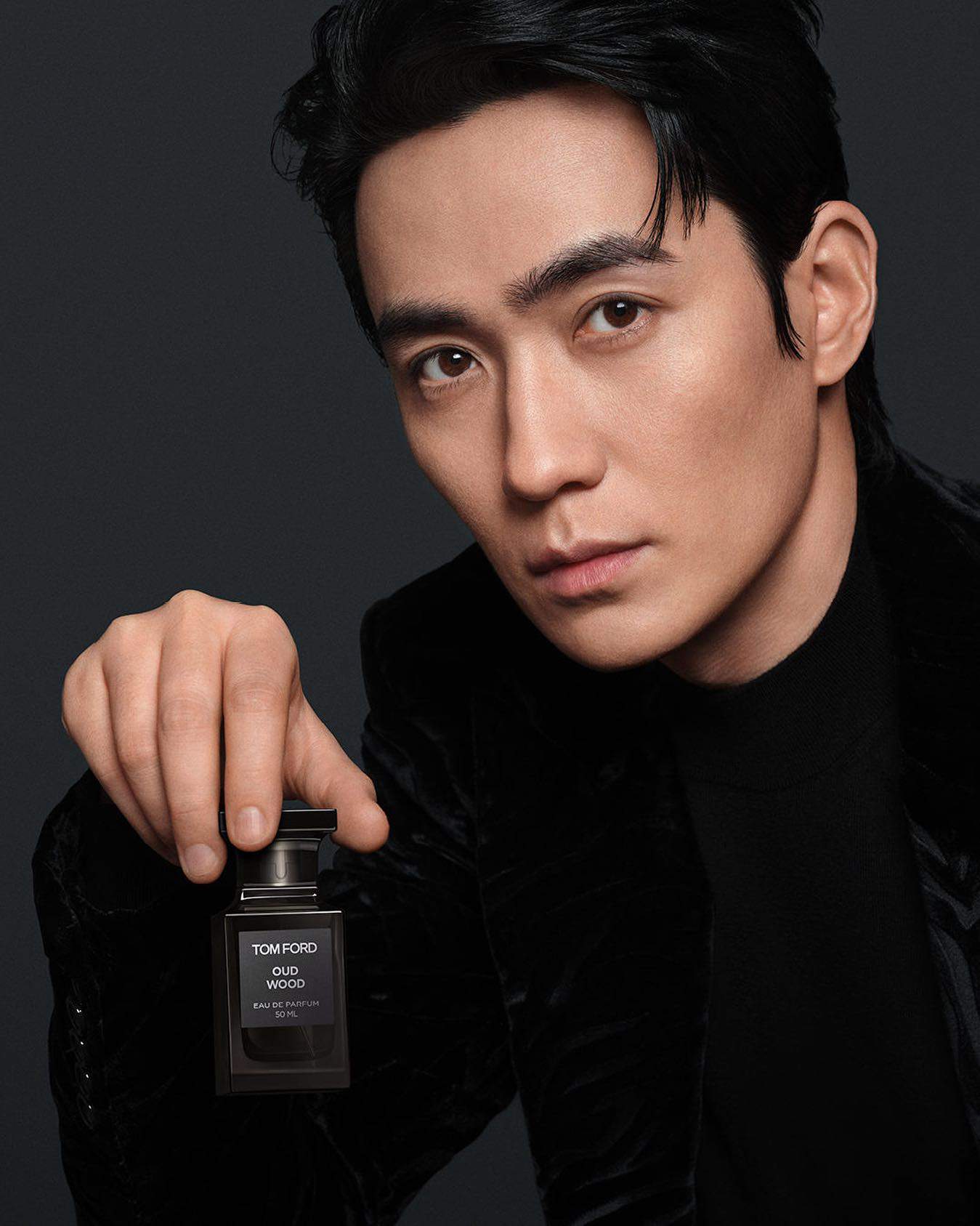 man holding a bottle of tom ford oud wood cologne
