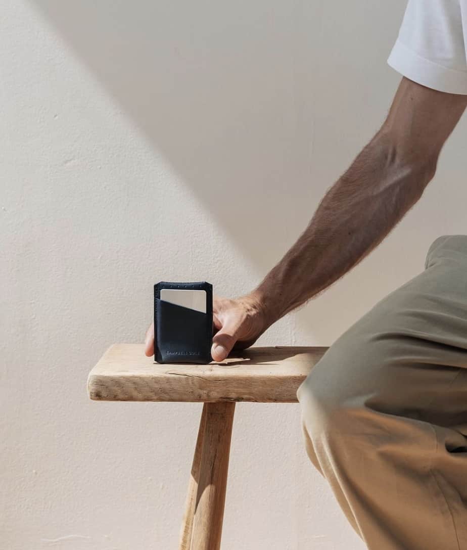 man sitting on a bench showing off a small wallet