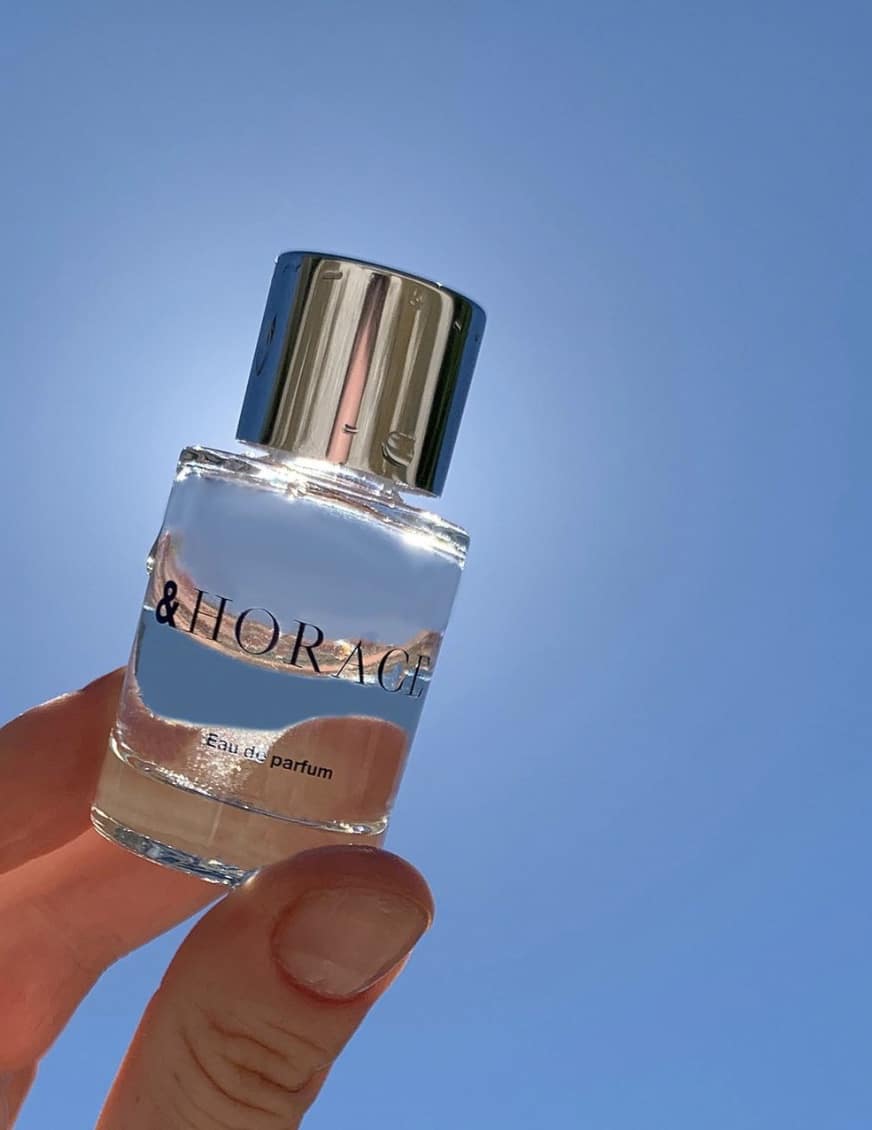 hand holding up perfume bottle to sun