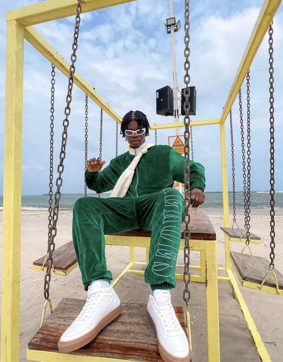 man sitting on a swing on at a beach in a matching jumpsuit