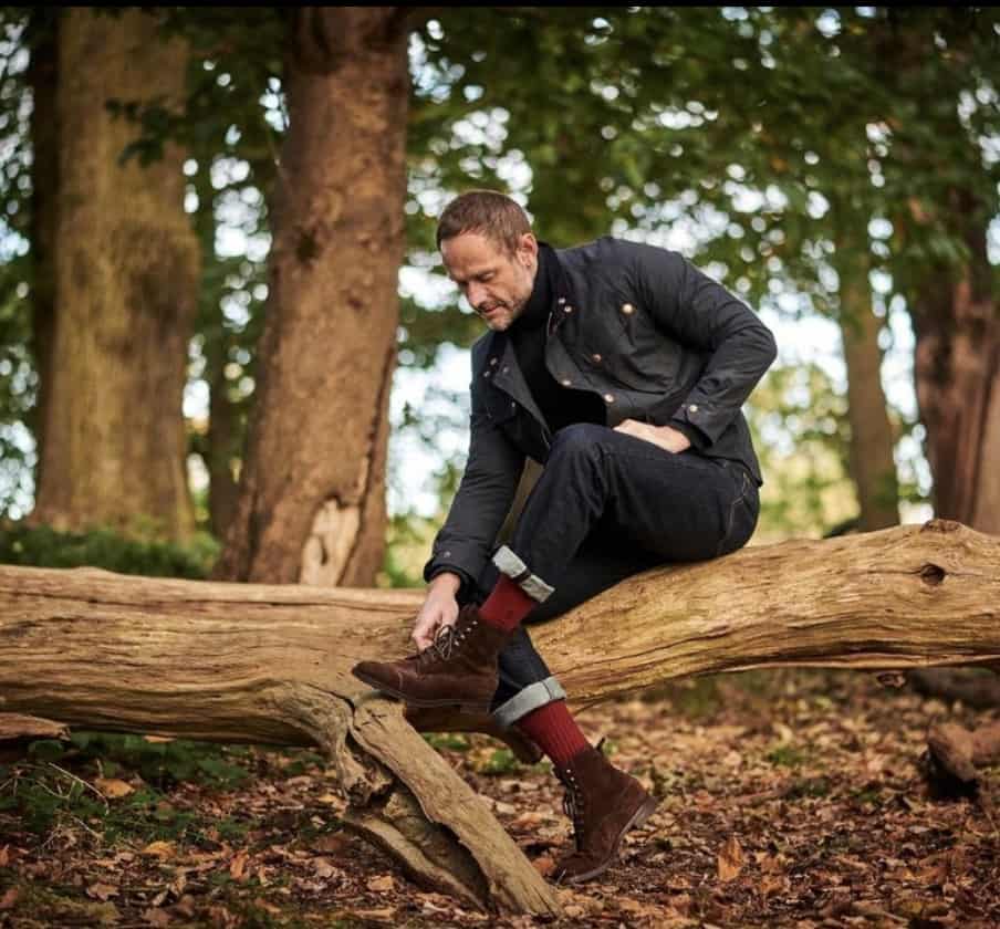 man sitting on a big log in the forest 