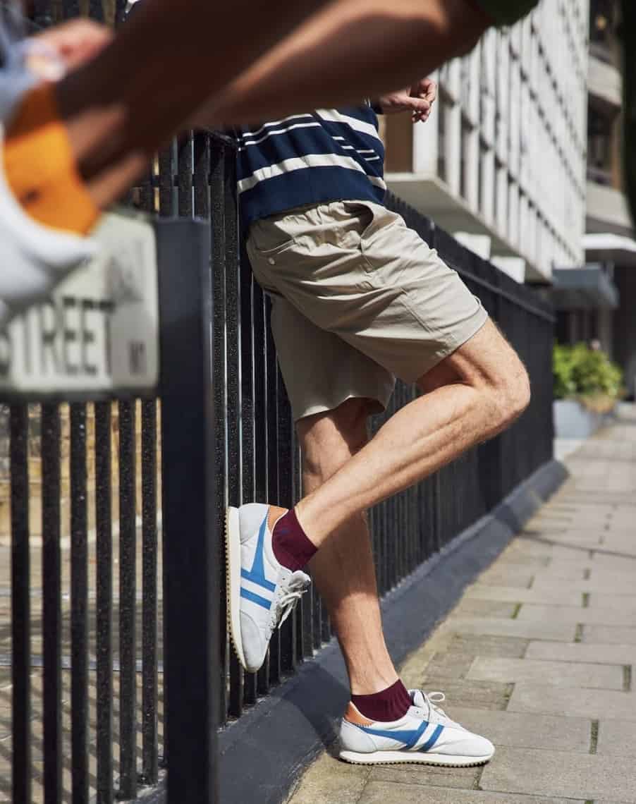 Man leaning against a iron fence, showing off the best ankle socks from London Sock Co. Blurry ankle in the top left. 