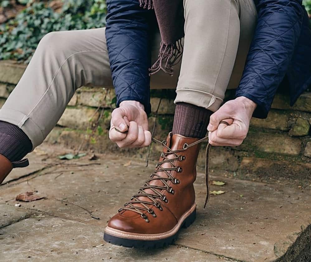 man tying his boot, sitting on a curb