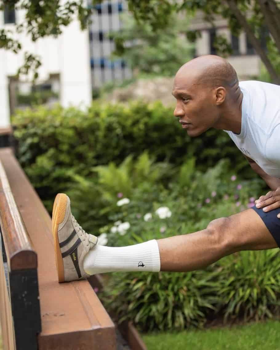 man stretching with his foot up on a railing 