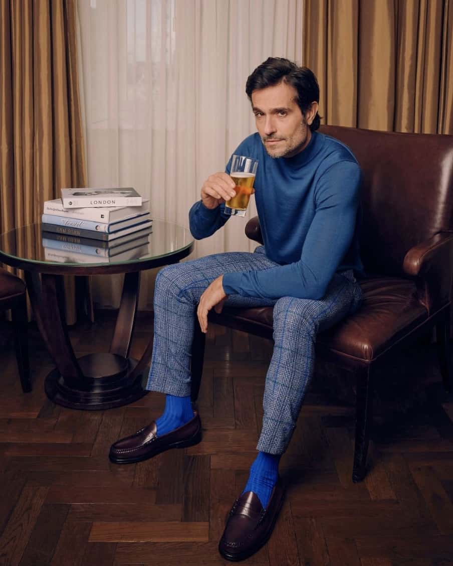 man sitting in a chair wearing business casual, holding a beer, looking at the camera 