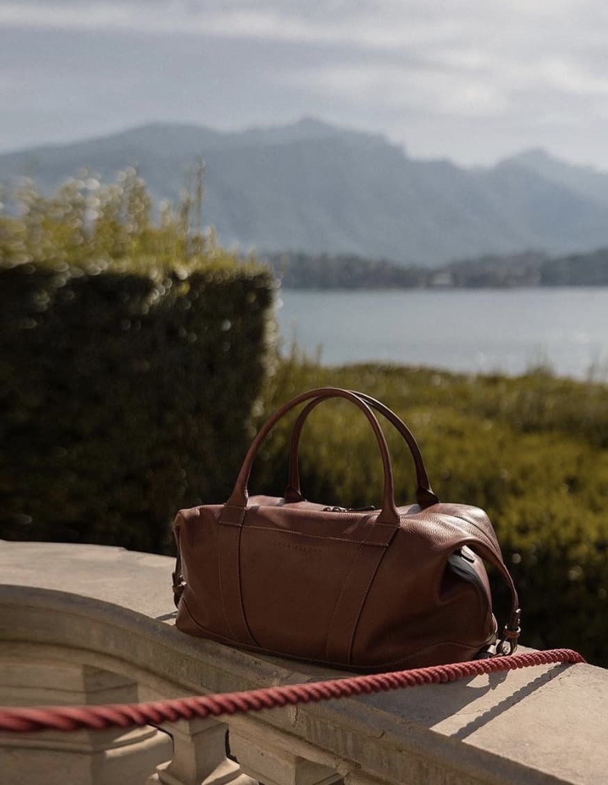 luca faloni leather weekender bag on a balcony 