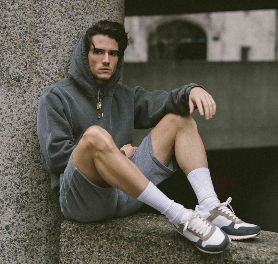 Man sitting on a concrete ledge, feet up, hands on knees