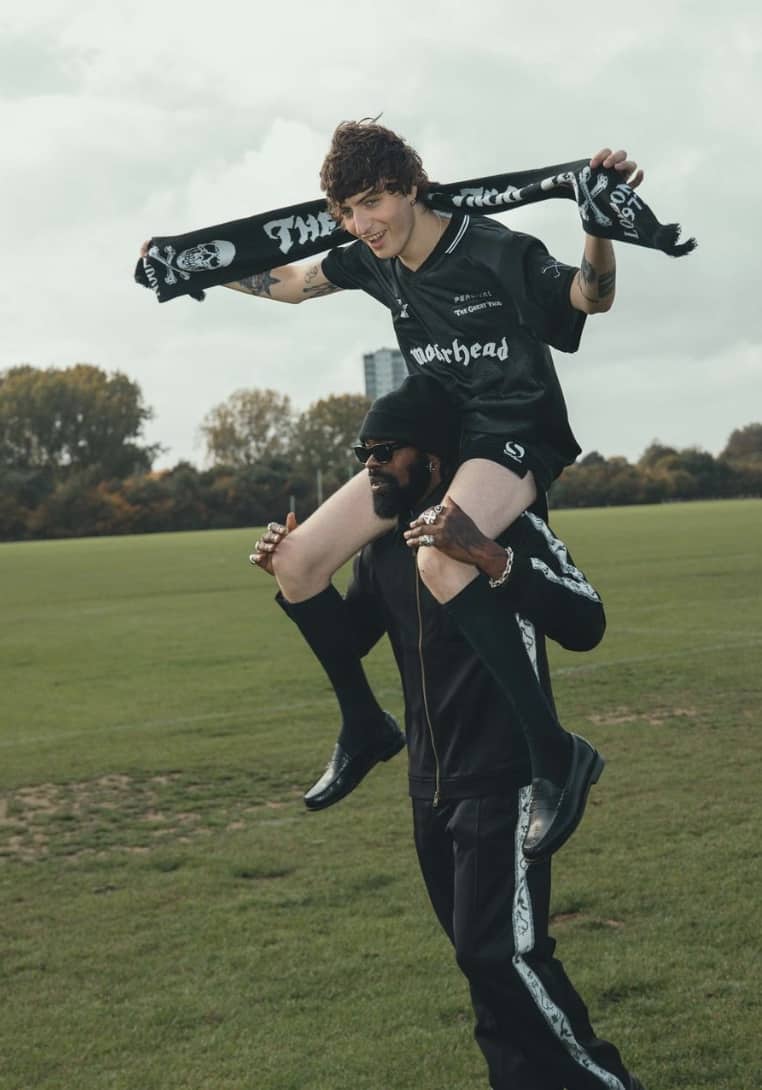 man sitting on anothers shoulder in a soccer uniform