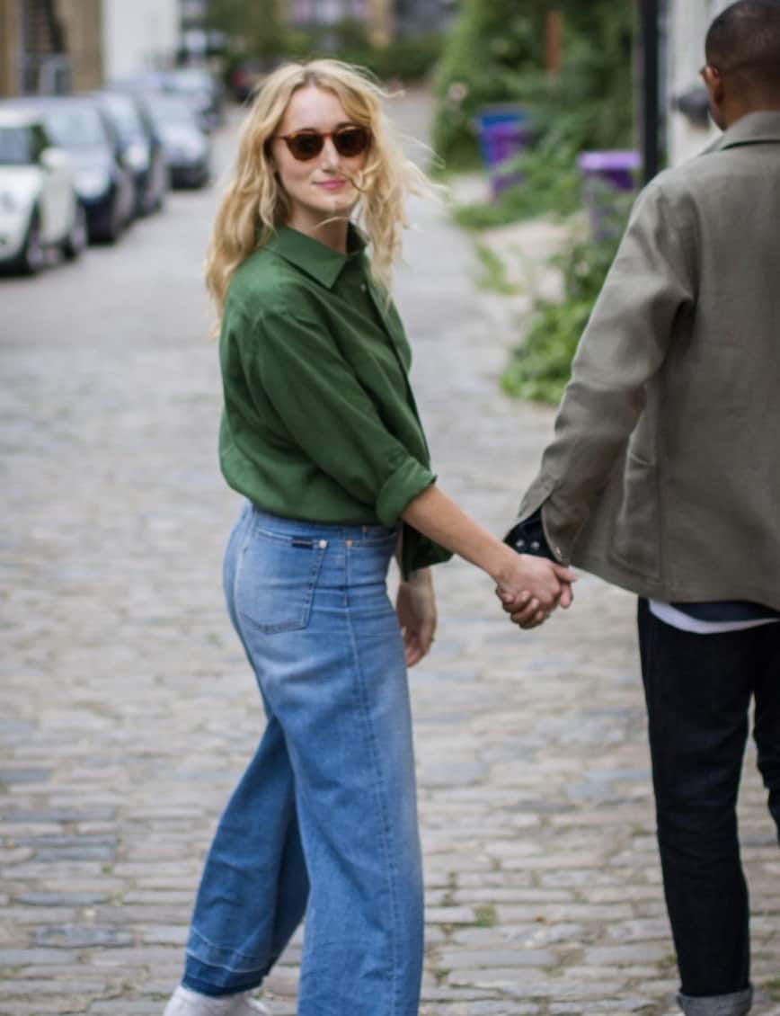 man and women holding hands walking down the street, women looking at the camera