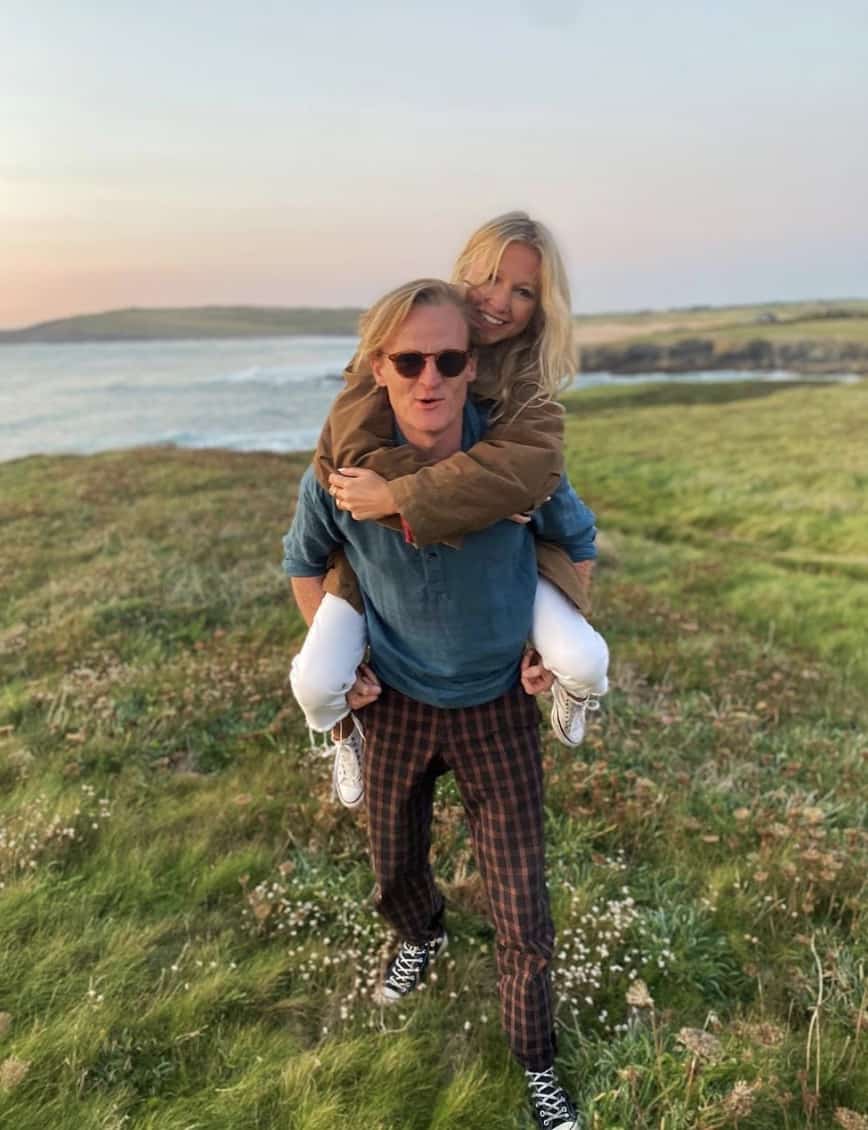 women on a man's back, in a field, both smiling at the camera 